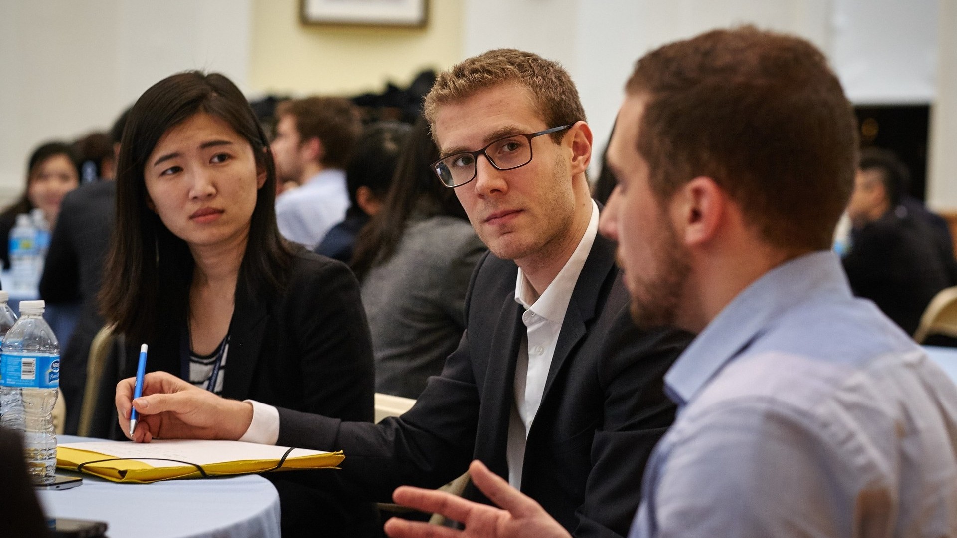 Professionals in business attire engaged in conversation at a formal event or networking session.
